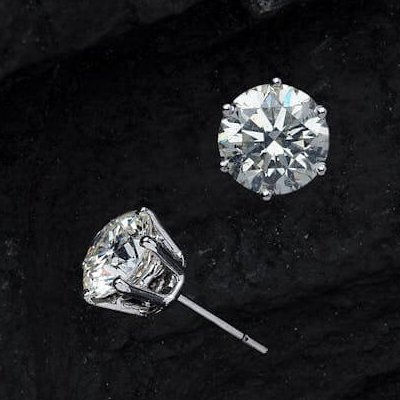 Round brilliant diamond stud earrings on black textured background Ideal Jewelers home page category header