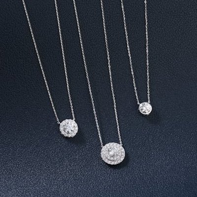 Multiple diamond pendant necklaces on textured navy background Ideal Jewelers home page category header